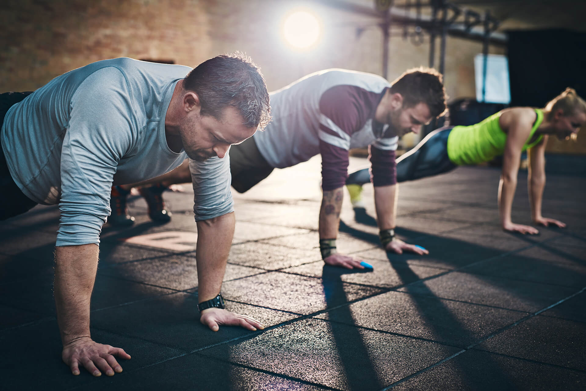 People doing push-ups in a gym, showing why regular exercise is important for health.